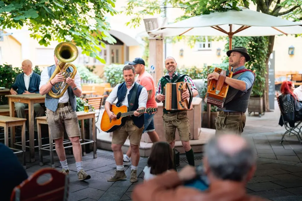 Blasmusikgruppe spielt in Tracht in einem Gastgarten in Österreich mit Gitarre und Ziehharmonika